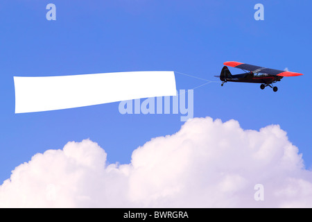 Un aeroplano che vola attraverso il cielo tirando un fustellato banner bianco per aggiungere il proprio messaggio. Foto Stock