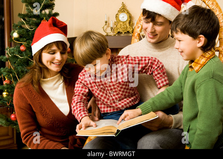 Immagine dei membri della famiglia la lettura di favole insieme a casa Foto Stock