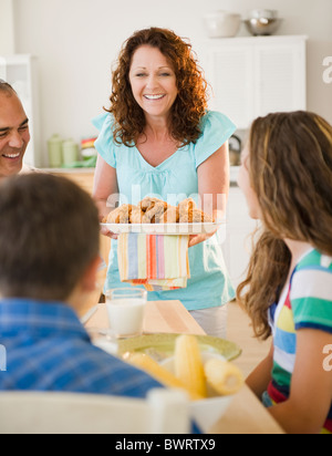 Donna sorridente che serve cena di famiglia Foto Stock