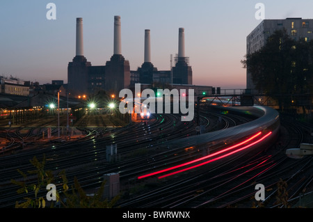 I treni che entrano e lasciano la stazione di Victoria in serata Rush Hour con Battersea Power Station in background. Foto Stock