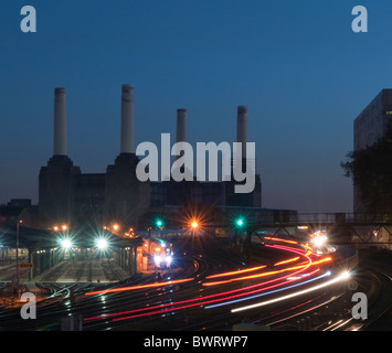 I treni che entrano e lasciano la stazione di Victoria in serata Rush Hour con Battersea Power Station in background. Foto Stock