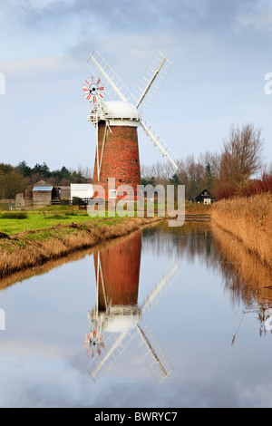 Horsey, Norfolk, East Anglia, Inghilterra, Regno Unito. Horsey mulino rosso mattone torre pompa di vento si riflette in una diga di drenaggio in Norfolk Broads Foto Stock