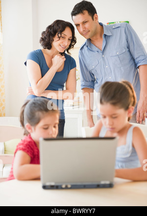 Il padre e la madre a guardare i bambini utilizzando internet insieme Foto Stock