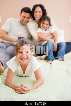 La famiglia felice la posa sul letto insieme Foto Stock