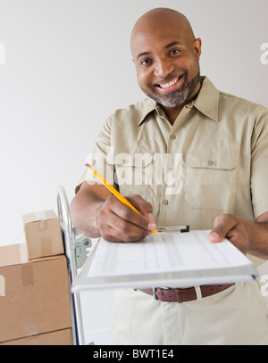 African American deliveryman tenendo fuori appunti per la firma Foto Stock