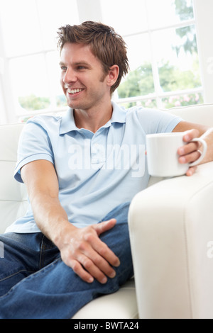 Uomo seduto sul divano di bere il caffè in un momento di relax a casa