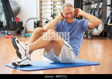Senior uomo facendo sit ups in palestra Foto Stock