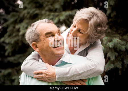 Ritratto di femmina senior abbracciando il marito mentre lui ridendo e guardando il suo Foto Stock