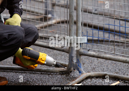 Un operaio rafforza una folla barriera di controllo in fase di preparazione per gli studenti protestano contro le tasse di iscrizione Foto Stock