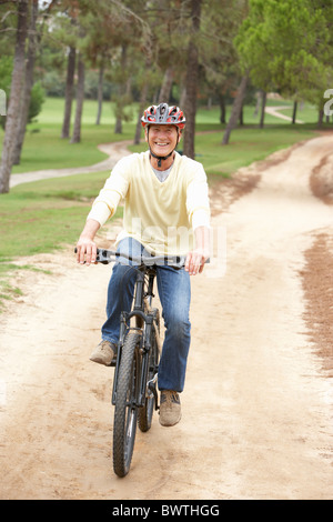 Un giovane uomo che cavalca in bicicletta nel parco Foto Stock