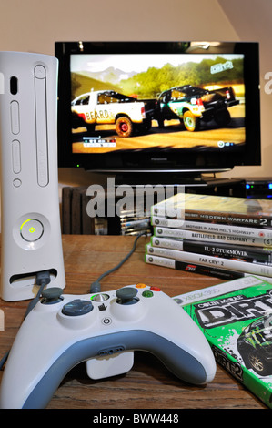 Console del controller e pila di video giochi nella parte anteriore dello schermo del televisore che mostra le vetture nel gioco di corse Foto Stock
