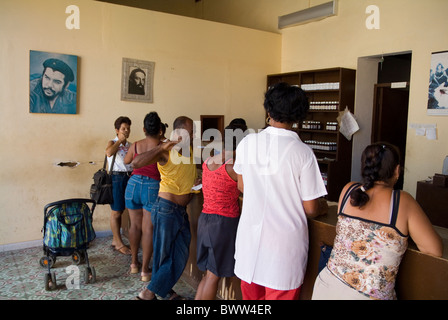 I clienti in una farmacia con Che Guevara ritratti sulle pareti, Trinidad, Sancti Spiritus, Cuba. Foto Stock