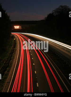 Sentieri di luce del traffico in movimento presa da sopra la strada a doppia carreggiata con una illuminazione a messaggio variabile nel segno della distanza. Foto Stock