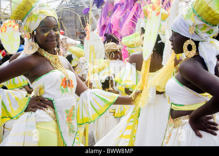 Trinidad Carnevale - Due ragazze con le mani sui fianchi in bianco floreale e costume giallo, cestelli sulle loro teste Foto Stock