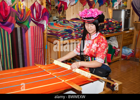 Mosuo donna tessitura abbigliamento colorato nel suo negozio, Lijiang, nella provincia dello Yunnan in Cina Foto Stock