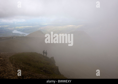 Due escursionisti sul percorso di Llanberis per Snowdon vertice. Affacciato su Cwm Glas attraverso eliminazione cloud. Llyn Beris visibile. Foto Stock