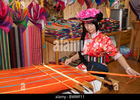 Mosuo donna tessitura abbigliamento colorato nel suo negozio, Lijiang, nella provincia dello Yunnan in Cina Foto Stock