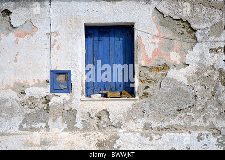 Deterioramento incrinato adobe parete con blu finestra ritagliata. Foto Stock