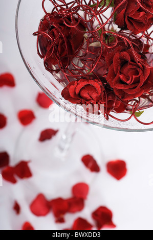 Floreale moderno centro tavola utilizzando il rosso dei petali di rosa e rosso metallizzato filo in un grande e alto calice Foto Stock