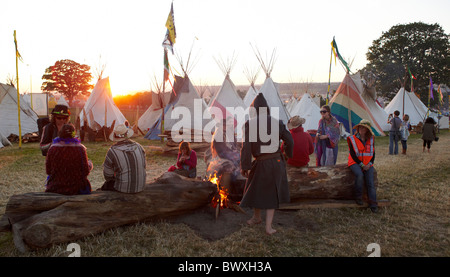 Persone sedute intorno ad un incendio presso il festival di Glastonbury Somerset REGNO UNITO Europa Foto Stock