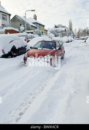 Piccolo rosso Renault Clio aziona attraverso la neve profonda lungo una coperta di neve su strada. Foto Stock