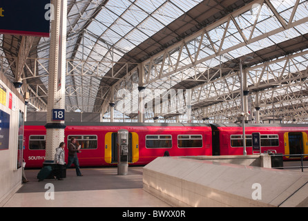 Passeggeri a piedi a bordo delle loro a sud-ovest di treni treni passeggeri sulla via 18 alla stazione Waterloo di Londra a Lambeth, Londra, Inghilterra, Regno Unito. Foto Stock