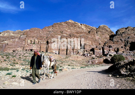 Petra, Giordania - uomo a camminare con il suo cavallo vicino all'ingresso della Royal tombe scavate nella roccia di Petra Foto Stock