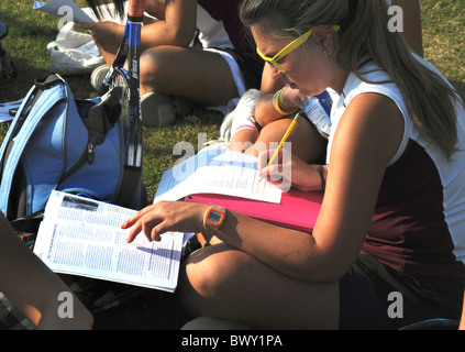 Ragazza adolescente non lavori scolastici mentre ella attende di giocare a tennis Foto Stock