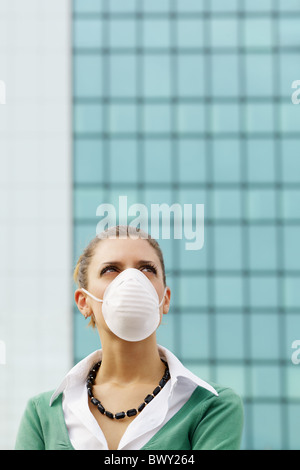 Donna in piedi contro la costruzione di ufficio e di indossare la maschera protettiva. Spazio di copia Foto Stock