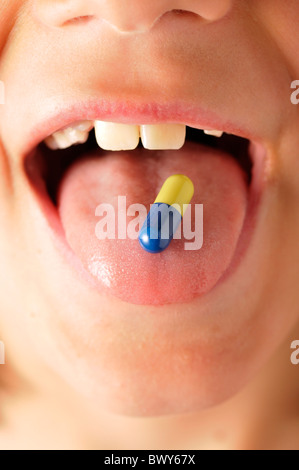 Ragazzo con capsule sulla linguetta Foto Stock