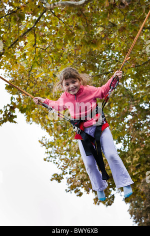 Bambino, una ragazza piccola che salta usando una corda saltante da solo, tirata  di stile di vita all'aperto. Capretto usando una corda di salto fuori.  Bambini in età scolare e a fisica