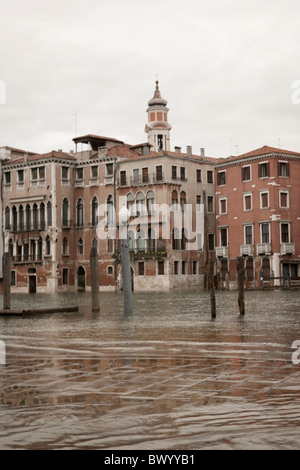 Fuoriuscite di acqua al di sopra del bordo del Canal Grande a Venezia a marea alta. Foto Stock