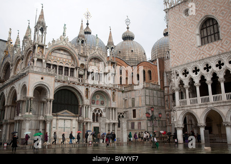 I turisti con ombrelloni utilizzando le passerelle per mantenere i piedi asciutti al di fuori la Basilica di San Marco a Venezia. Foto Stock