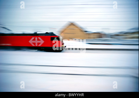 Uno Svizzero Intercity whizzing attraverso una coperta di neve città in pieno inverno. Motion Blur utilizzato per dare il senso della velocità Foto Stock