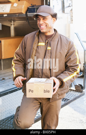 Sorridente consegna ispanica uomo con scatola di cartone Foto Stock