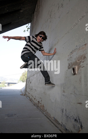 Razza mista ragazzo adolescente salta fuori da parete Foto Stock