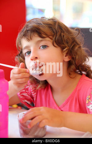 Ragazza di mangiare il gelato al cioccolato faccia sporca avendo divertimento Foto Stock