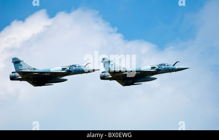 Due Mirage 2000 velivolo francese Air Force Armée de L'air tailing a ciascun altro attraverso il cielo - sfondo cloud Foto Stock