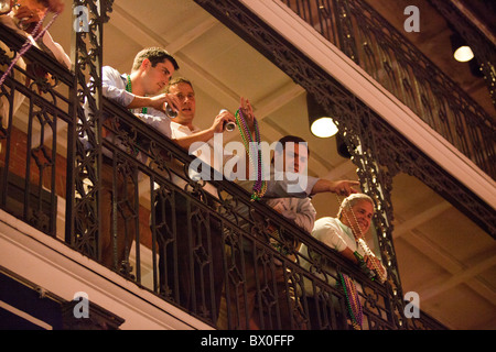 I turisti gettano Mardi Gras perle per gente camminare sotto su Bourbon Street a New Orleans, Louisiana del Quartiere Francese. Foto Stock