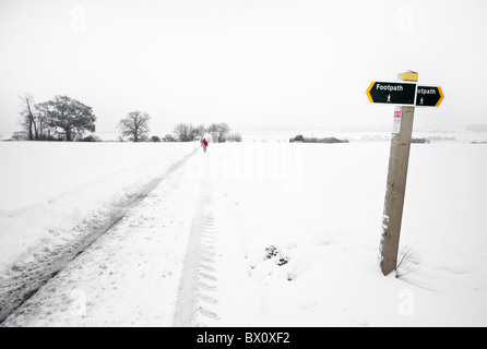 Lone uomo a camminare nella neve in distanza. Foto Stock