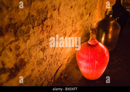 Demijohn vetro di vino rosato lighten up dalla candela Foto Stock