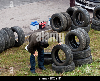 Un uomo esamina attentamente di seconda mano pneumatici visualizzati in un mercato delle pulci nella periferia di Gothenburg, Svezia. Foto Stock