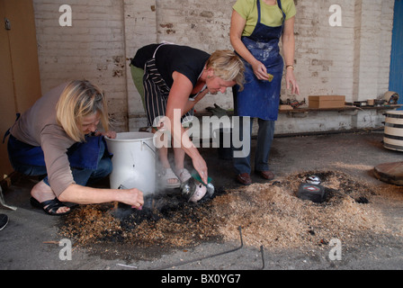 Fare ceramica Raku utilizzando un tradizionale riservato di cottura in ceramica Foto Stock