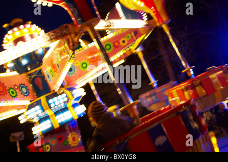 I bambini su fairground ride al crepuscolo Foto Stock