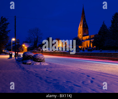 Rutland, Inghilterra. Il passaggio di vetture lasciano scie di luce nel villaggio di Cottesmore come Aurora rompe con neve fresca sul terreno. Foto Stock
