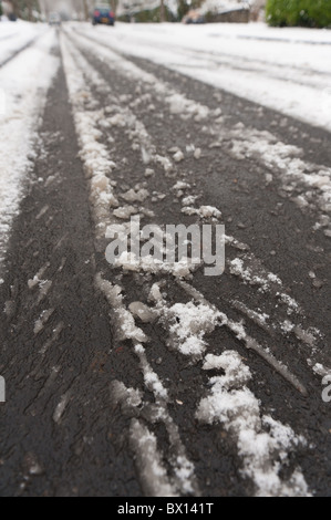 Buche e fusione runoff di neve in una strada di campagna causati dalla neve e dal gelo Foto Stock