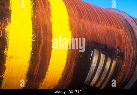 Grande tubo metallico con leggermente la superficie arrugginita e giallo e argento strisce ID verniciato e impresse su e cielo blu Foto Stock