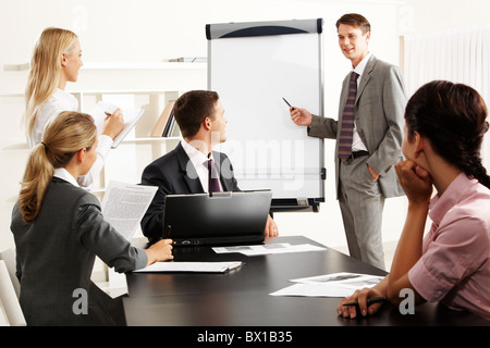 Immagine della Smart Business persone che guardano il loro leader mentre lui spiegare qualcosa su whiteboard durante il seminario Foto Stock