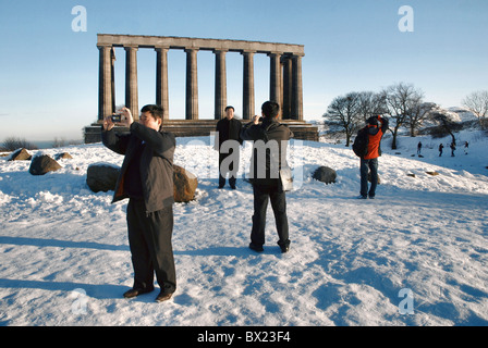 I turisti scattare fotografie presso il monumento nazionale su Calton Hill a Edimburgo dopo un inizio di dicembre nevicata. Foto Stock