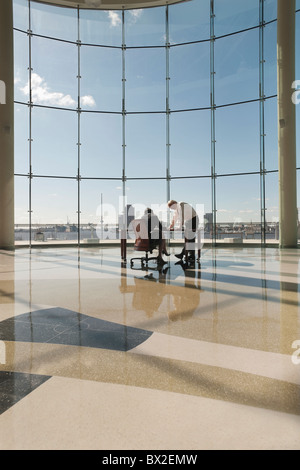 La gente di affari che lavorano in uffici di grandi dimensioni con parete in vetro Foto Stock